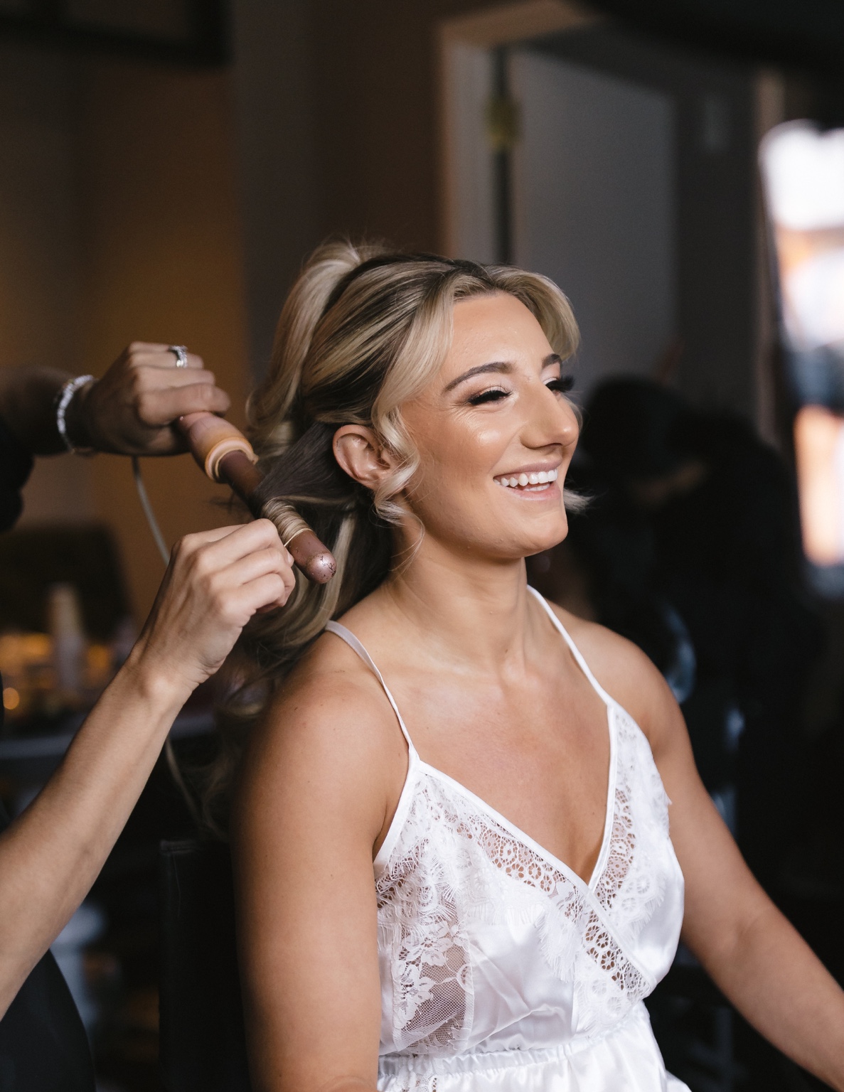 Bridal hair stylist curling a bride’s hair during the wedding morning