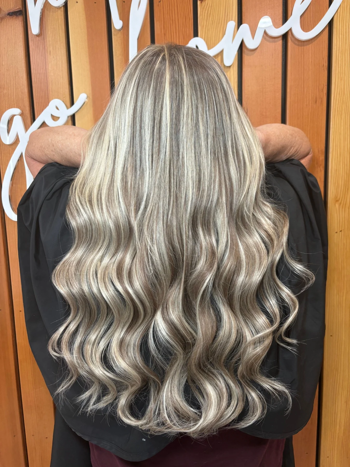 Long dimensional blonde waves styled at Entyre with the salon backdrop visible